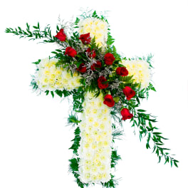 White floral cross with red roses arranged diagonally across the center