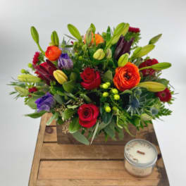 Mixed bouquet in a wooden box with a small candle beside it