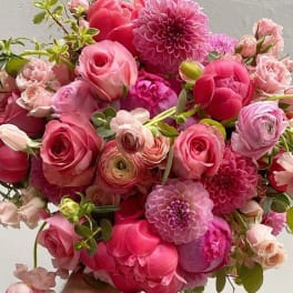 Bouquet of pink roses, peonies, and dahlias with small green accents