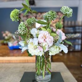 Mixed floral arrangement in a clear glass vase with green and white blooms