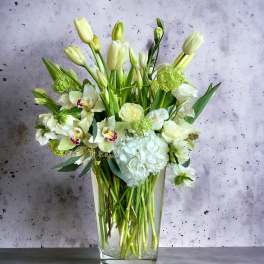 White and pale green floral arrangement in a clear glass vase