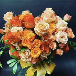 Bouquet of orange, peach, and white roses with a gold ribbon