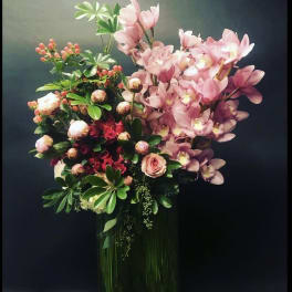 Pink orchids and roses arranged in a tall vase