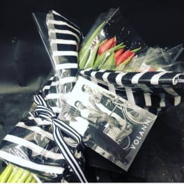 Wrapped bouquet of red tulips with black-and-white striped paper