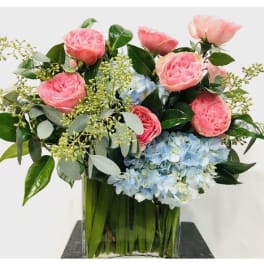 Pink roses and blue hydrangeas in a clear glass vase