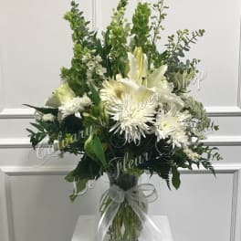 White lilies and daisies in a glass vase with a ribbon bow