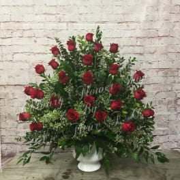 Large arrangement of red roses in a white pedestal vase