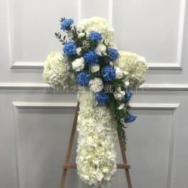 White and blue floral cross on a wooden easel