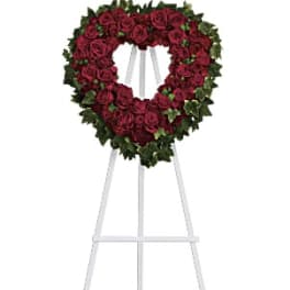 Heart-shaped red rose wreath on a white easel