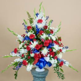 Tall red, white, and blue floral arrangement in a white vase