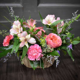 Pink and white flowers arranged in a woven basket