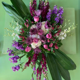 Large pink and purple floral arrangement with broad green leaves