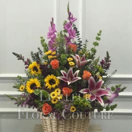 Basket arrangement with sunflowers, roses, lilies, and purple spikes