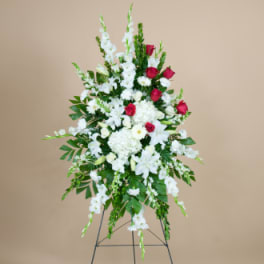 Tall standing floral spray with white flowers and red roses on a metal easel