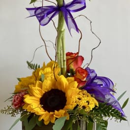 Sunflower arrangement in a wooden box with purple ribbon and roses