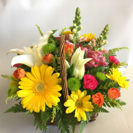 Basket arrangement with yellow daisies, white lilies, and pink and orange roses