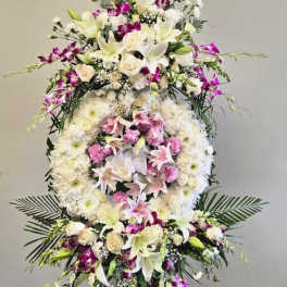 Large standing floral wreath with white lilies, roses, and pink orchids