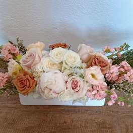 Low floral arrangement of pink and white roses in a white container