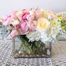Pink and white flower arrangement in a clear rectangular vase