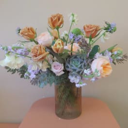 Peach roses and lavender flowers in a ribbed glass vase