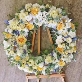 Large floral wreath on a wooden easel with white and yellow blooms