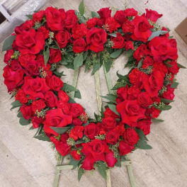 Heart-shaped arrangement of red roses with greenery