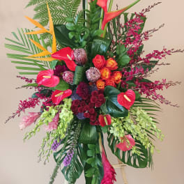 Tall tropical floral arrangement with orchids, anthuriums, and birds of paradise