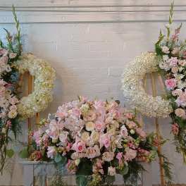 Three pastel floral wreaths and sprays on easels with a large pink centerpiece below.