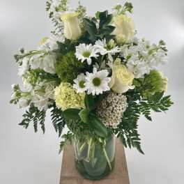 White and cream bouquet with roses, daisies, hydrangea, and green dianthus in a clear glass vase