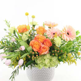 Orange roses and pale pink daisies in a white textured vase