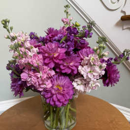 Pink and purple mixed flowers arranged in a clear glass vase