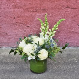 White roses and snapdragons in a green glass vase