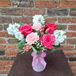 Pink roses and carnations in a vase with white flowers and a gingham ribbon