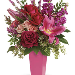 Pink and red floral arrangement in a tall pink vase