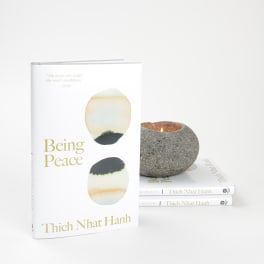 Book with a lit stone candle beside two stacked copies