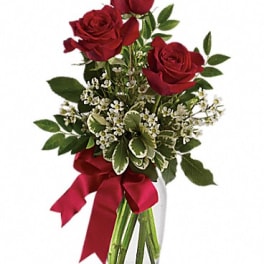 Red roses in a clear glass vase with a red ribbon