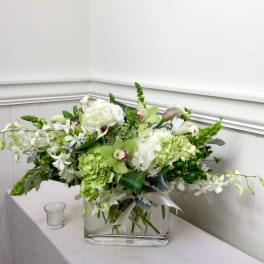 White and green floral arrangement in a clear rectangular vase