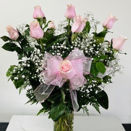 Pink roses in a clear glass vase with a pink bow
