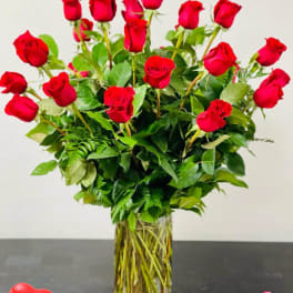 Tall vase of red roses with greenery