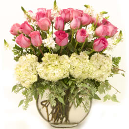 Round glass vase with pink roses and white hydrangeas in a full, rounded arrangement