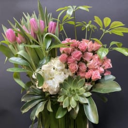 Pink tulips and roses arranged with white hydrangea in a glass vase