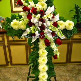 Cross-shaped floral tribute with red roses and white flowers on an easel