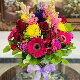 Bright mixed bouquet with roses, gerbera daisies, and snapdragons in a glass vase