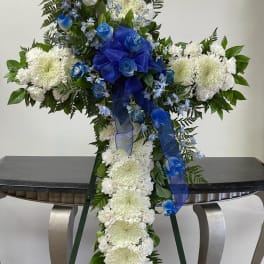 White and blue funeral spray with a blue ribbon on a stand