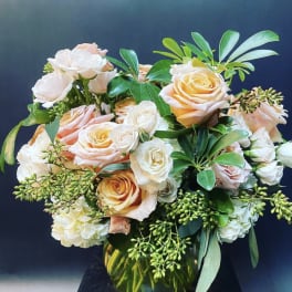 Peach and white roses arranged in a glass vase