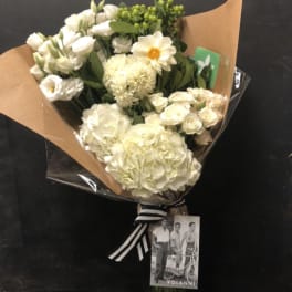 Bouquet of white flowers wrapped in brown paper with a striped ribbon