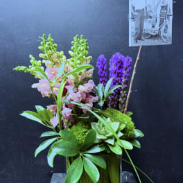 Pink snapdragons and purple flowers in a glass vase with succulents