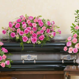 Pink floral sprays arranged around a black casket