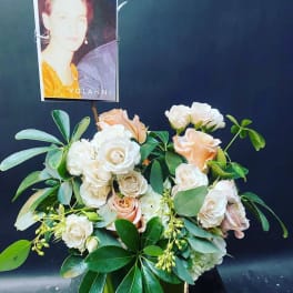 Floral arrangement of cream and peach roses with a photo card
