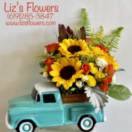 Sunflower and rose arrangement in a turquoise truck planter